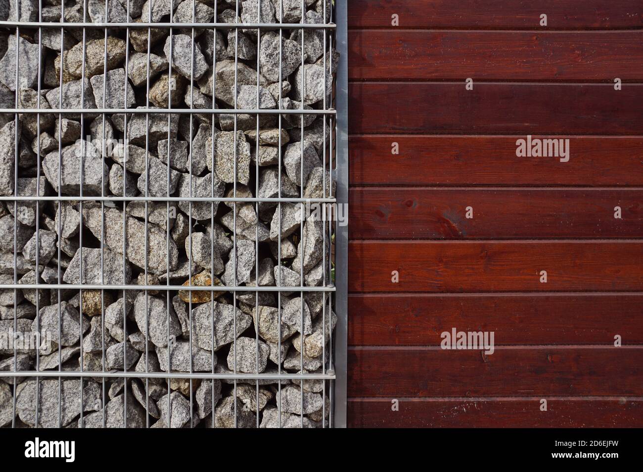 A combination of baskets filled with granite shards and painted boards. A fragment of a fence made of gabions. Stock Photo