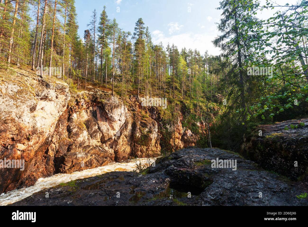 Oulanka National Park. Kiutaköngäs rapids waterfall with red limestone rock wall during a summery sunrise in Finnish nature, Northern Europe. Stock Photo