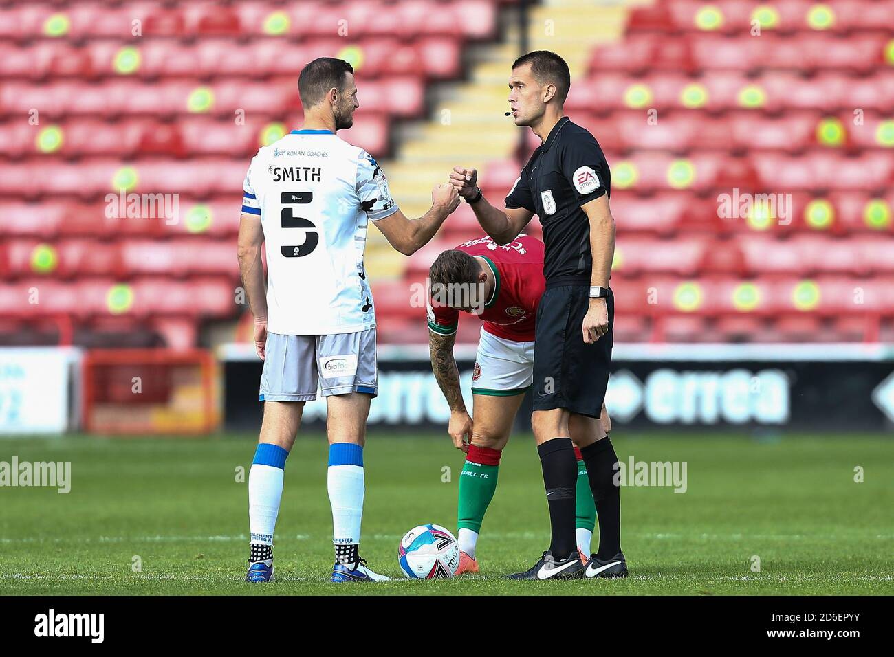 Tommy Smith (5) of Colchester United bumps fists with Referee Declan Ball. Stock Photo