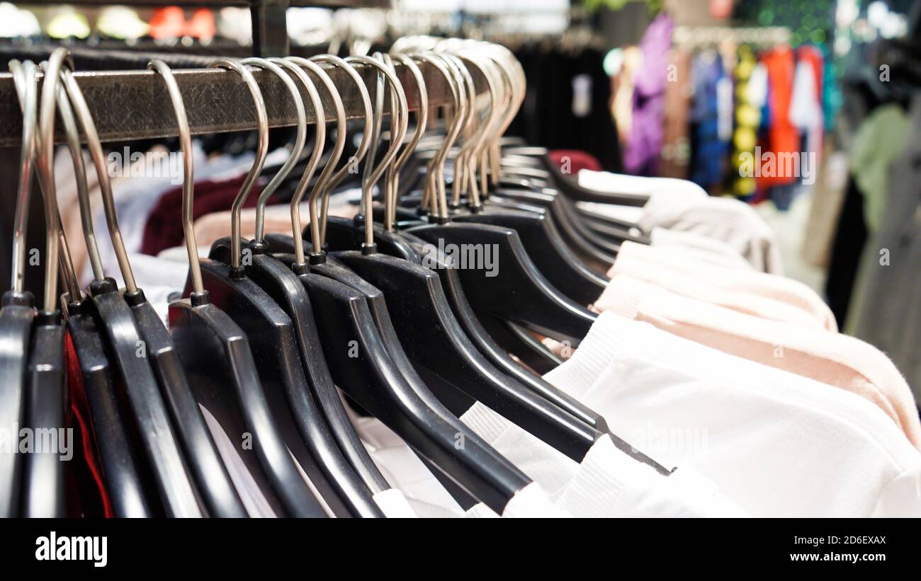 Close-up Modern fashionable women's clothing hangs on black plastic hangers in a department store of a clothing store. Online shopping for casual clot Stock Photo