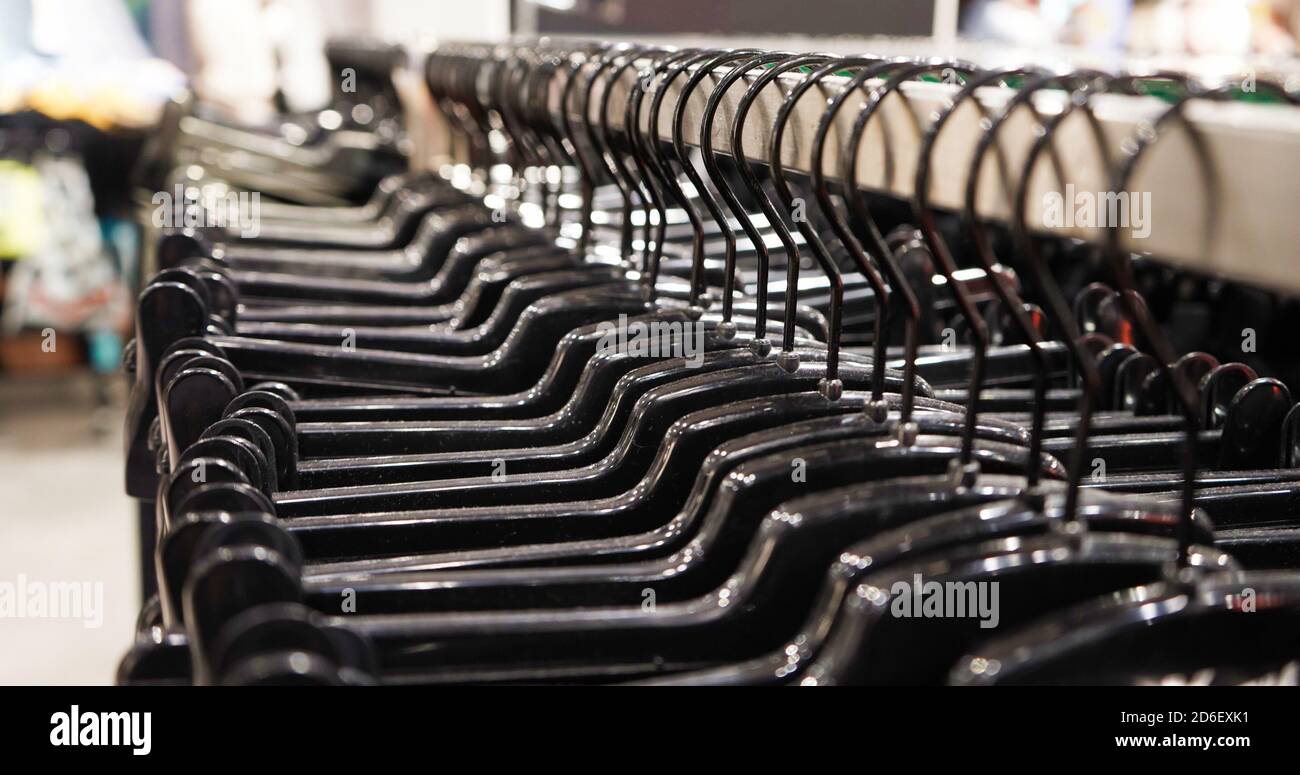 Close-up Modern fashionable women's clothing hangs on black plastic hangers in a department store of a clothing store. Online shopping for casual clot Stock Photo