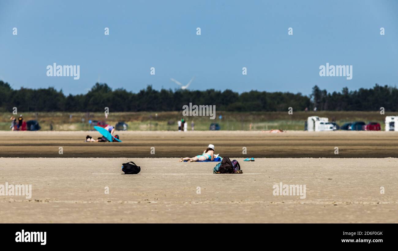 Woman with bikini and sun hat lies in the sand and sunbathes, St. Peter Ording, beach vacation Stock Photo