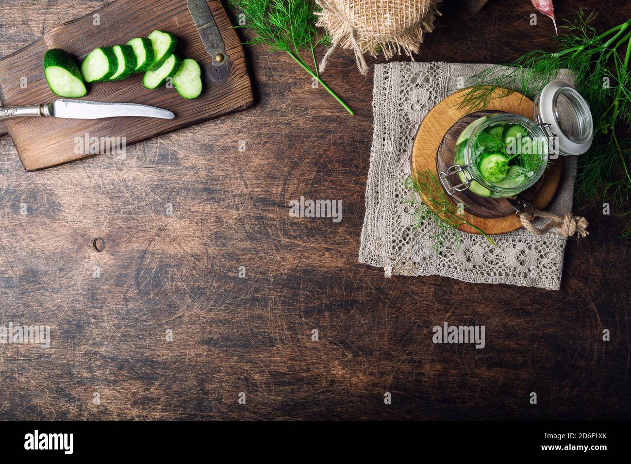 Preparation for pickling cucumbers. Homemade cucumbers cutted into slices with dill and garlic on rustic plywood background. Harvesting vegetables for Stock Photo