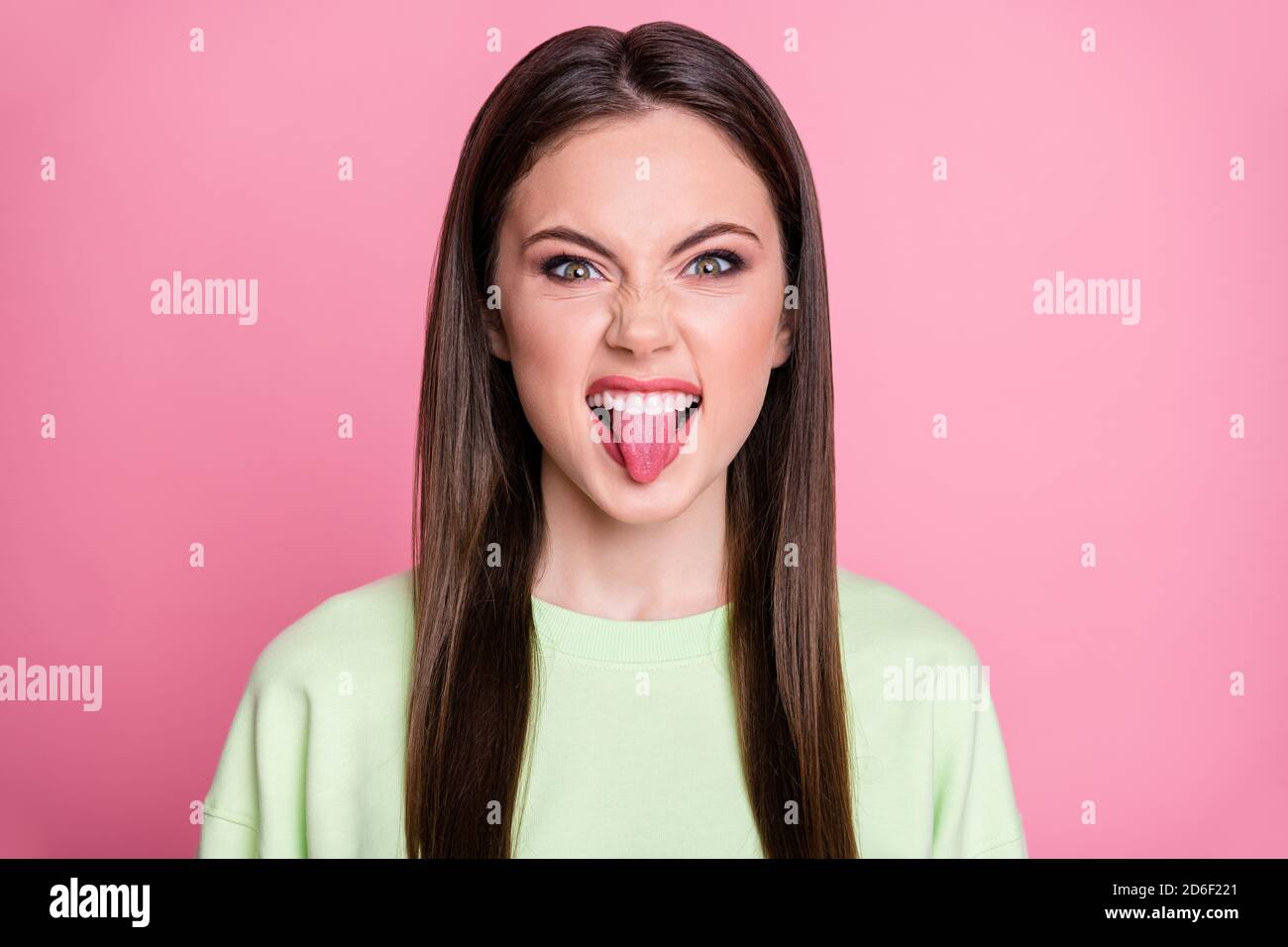 Closeup photo of funny attractive lady long hairdo girlish stick tongue mouth playful mood teasing boyfriend rude person wear casual green sweatshirt Stock Photo
