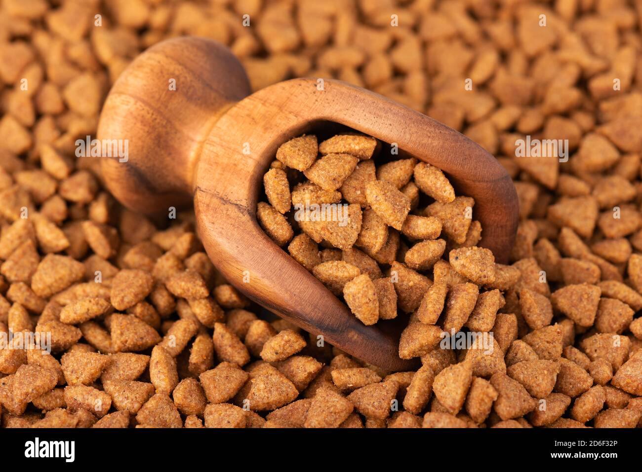 Dry pet food in wooden scoop. Pile of granulated animal feeds. Granules