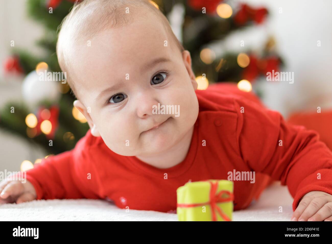 merry christmas christmas and happy new year, infants, childhood, holidays concept - close-up 6 month old newborn baby in red clothers on his tummy Stock Photo