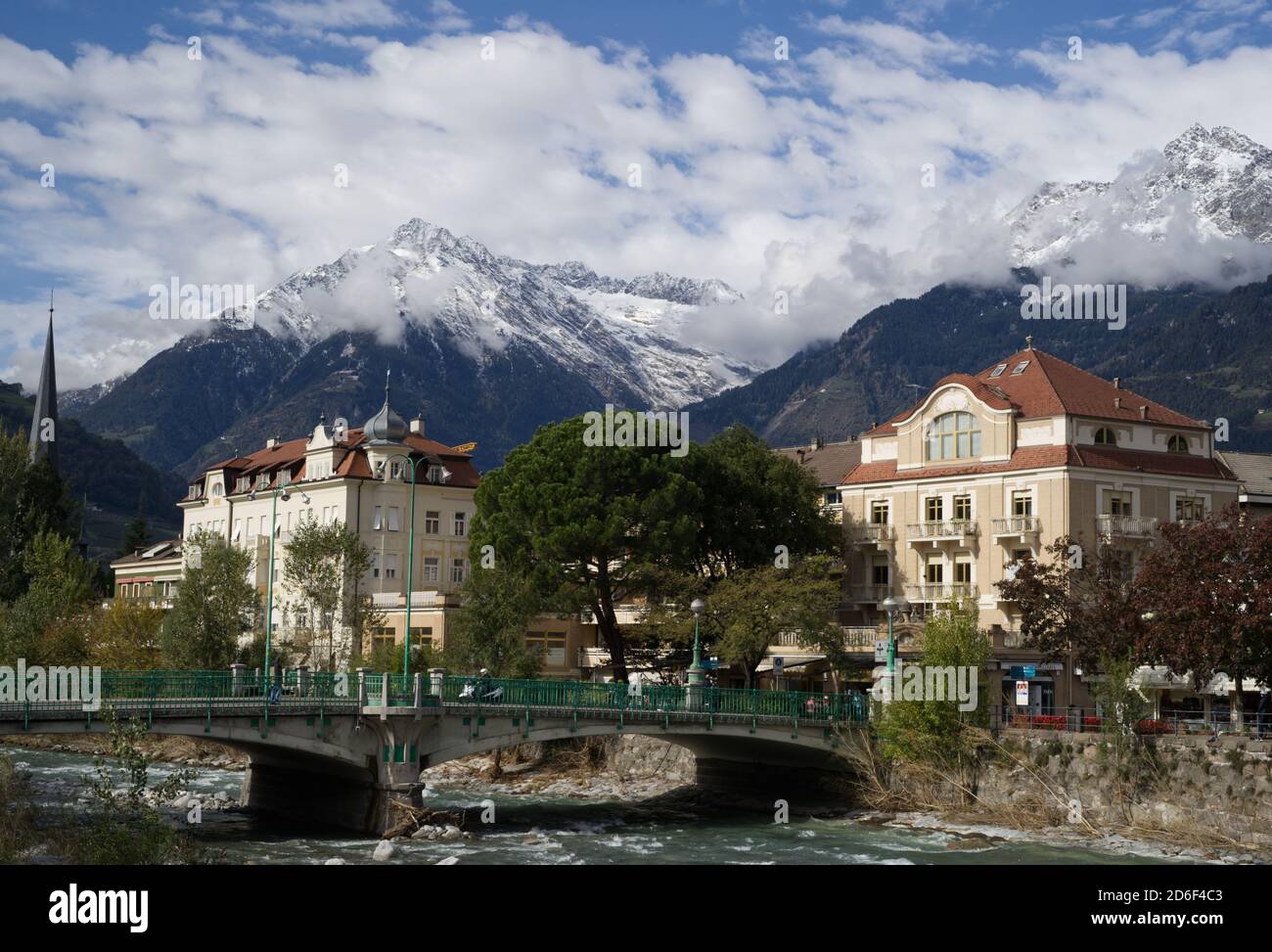 Merano spa-town in Italy in autumn, October 15th 2020. Bridge over the Passer river in foreground, Alps covered by snow in the background. Stock Photo
