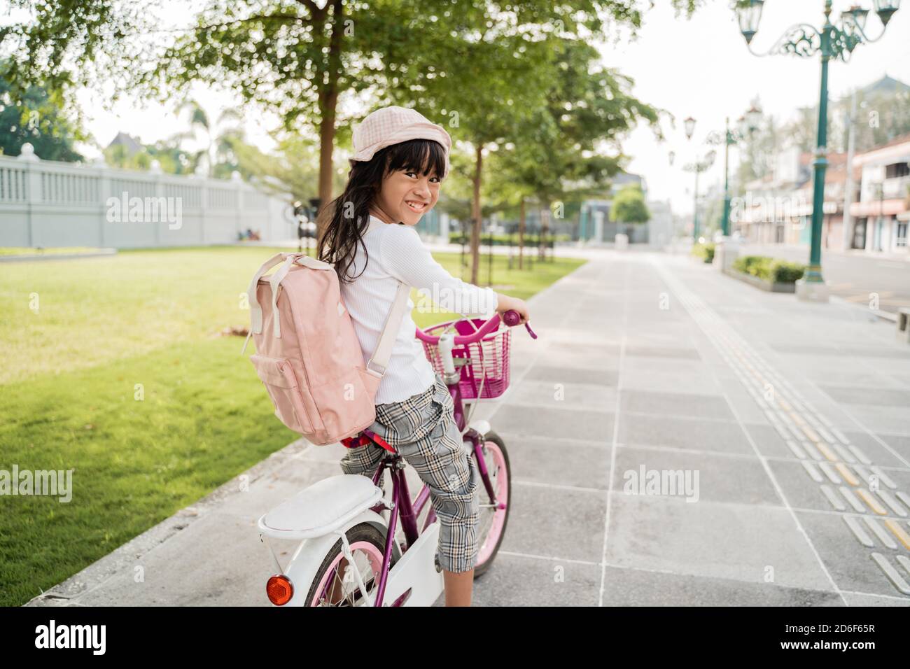 a portrait of a cheerful and happy little girl riding a bicycle in the park going to school by herself Stock Photo