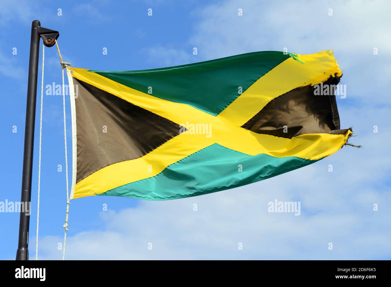 Flag of Jamaica waving against blue sky. Flag of Jamaica have a gold