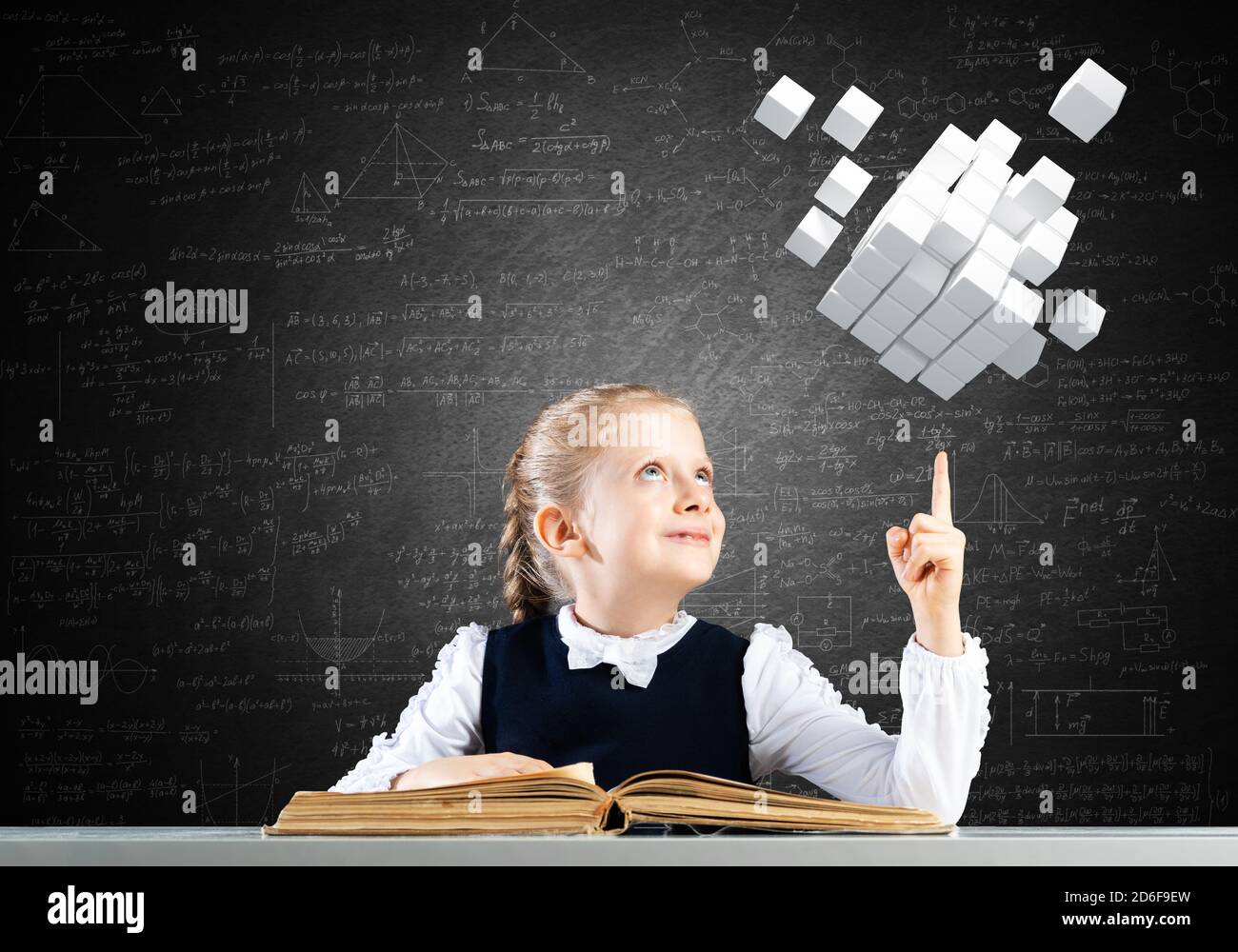 Smiling little girl sitting at desk with open book Stock Photo - Alamy