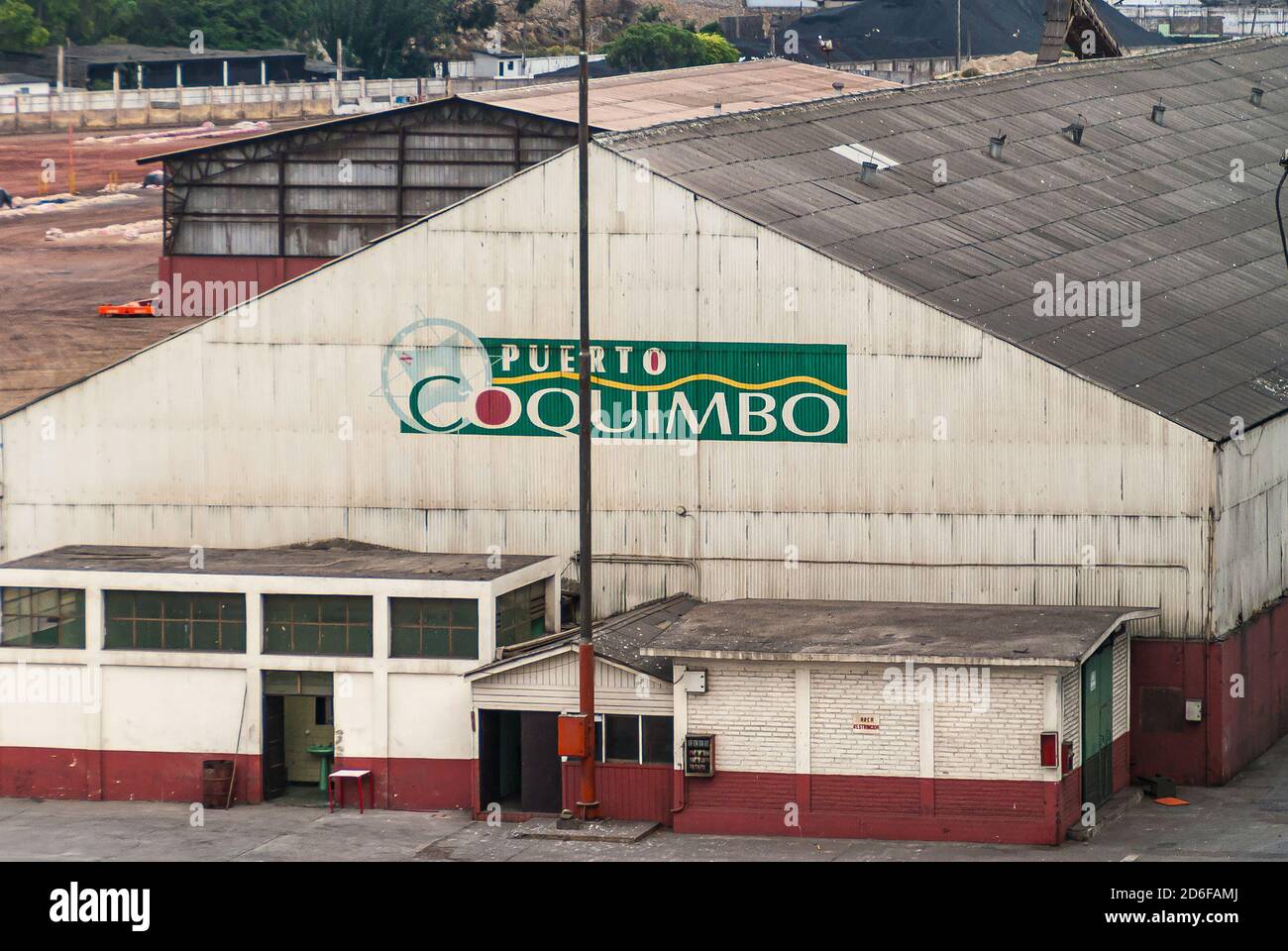 Coquimbo, Chile - December 7, 2008: White on green with red dots Puerto Coquimbo emblem on large white warehouse in port. Stock Photo