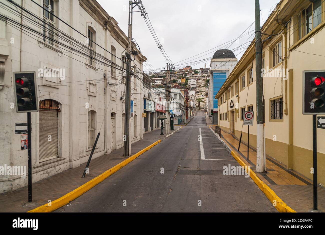 Coquimbo, Chile - December 7, 2008: Early morning produces an empty street with housing and closed businesses on both sides under silver sky. Stock Photo