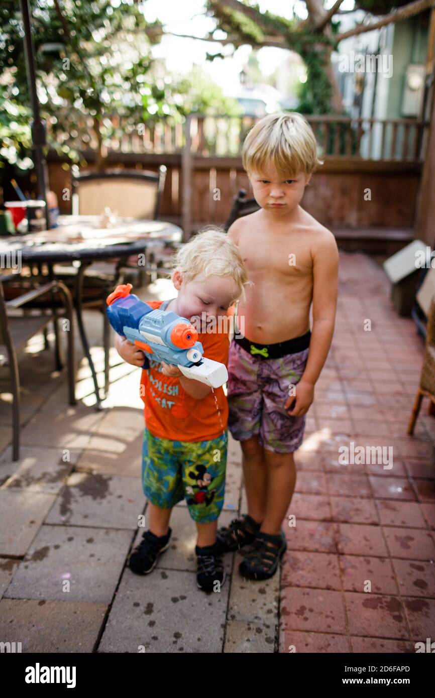 Brothers Standing Together on Patio Holding Water Gun Stock Photo - Alamy