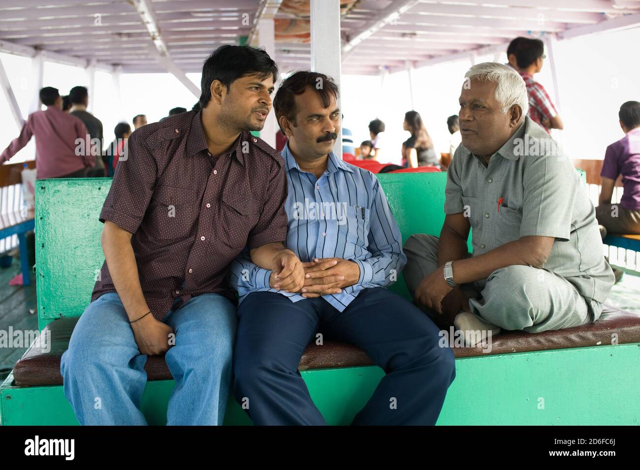 Three male friends sit together on board of a ferry, Mumbai, Maharashtra Stock Photo