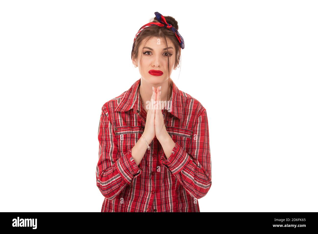 Head shot studio portrait millennial woman pose over white background looking at camera cupped hands in praying gesture feels sad desperate, symbol of Stock Photo