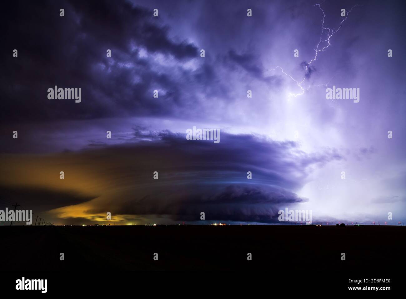 Lightning illuminates a supercell thunderstorm with dramatic storm clouds during a severe weather event over Dodge City, Kansas Stock Photo