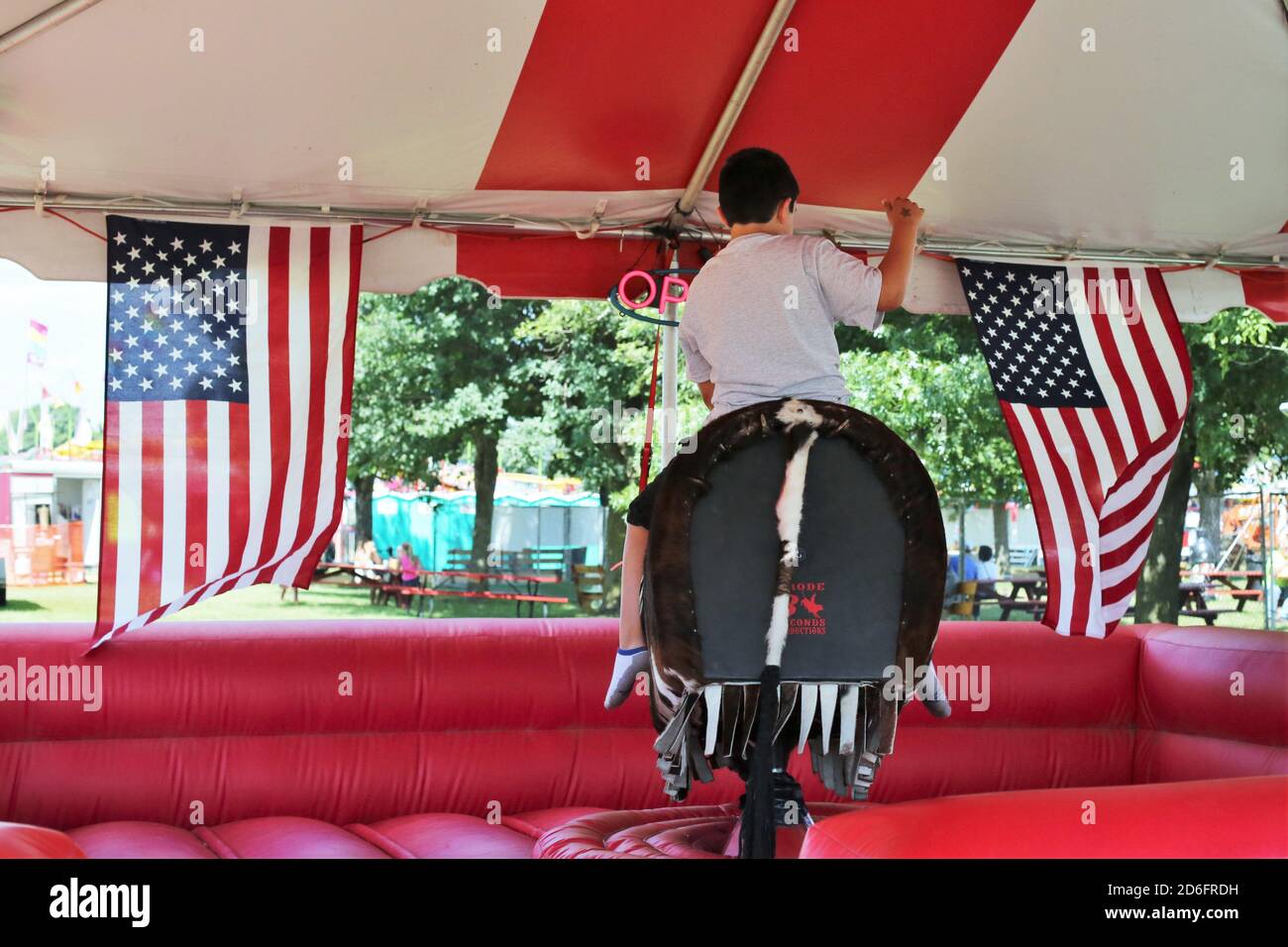 A kid riding a mechanical bull at the Steele County Fair in Minnesota. Stock Photo