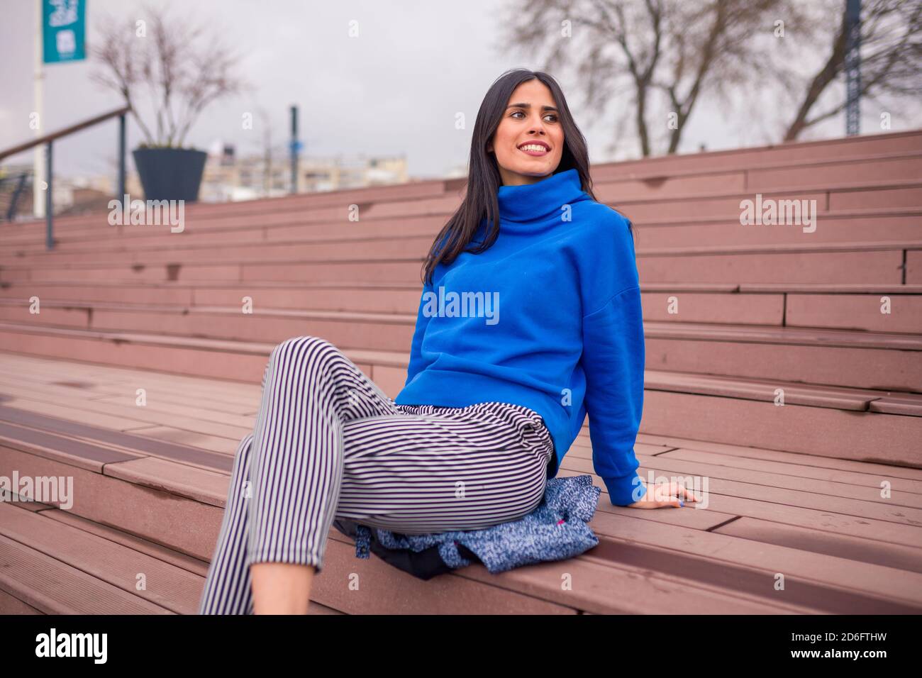 Beautiful girl sitting on the stairs. Looking away and smiling Stock ...