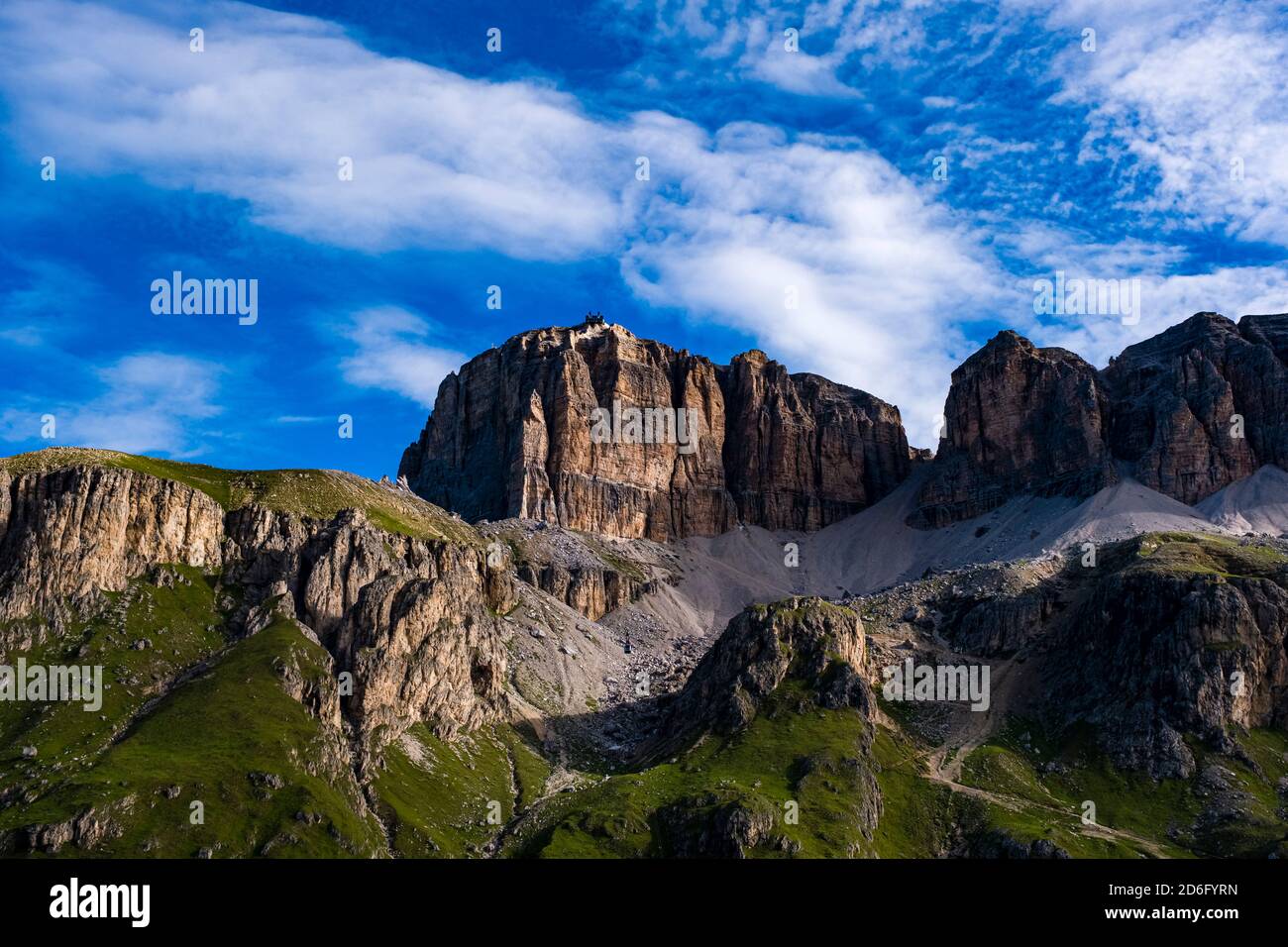 Steep rock cliffs of the plateau Sass Pordoi and the cable car station on top, seen from close to Pordoi pass, Passo Pordoi. Stock Photo