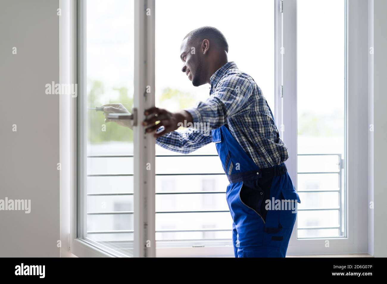 Young African Repairman In Overalls Installing Window Stock Photo