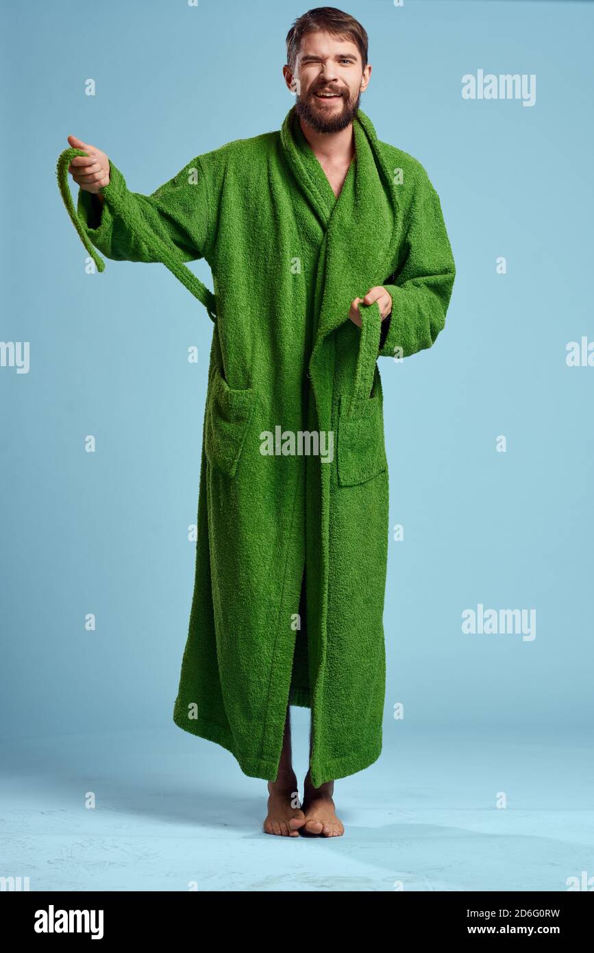 a man in a green robe in full growth on a blue background barefoot