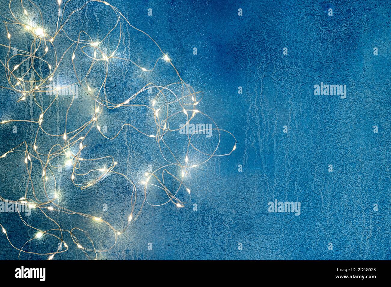 Christmas illumination lights on blue background. Abstract holidays compositions with christmas lights. Copy space, top view Stock Photo