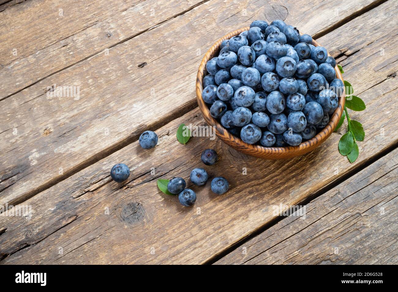 Fresh blueberry in wooden bowl. Juicy and fresh blueberries with green leaves on rustic table. Concept blueberry antioxidant for healthy eating and nu Stock Photo