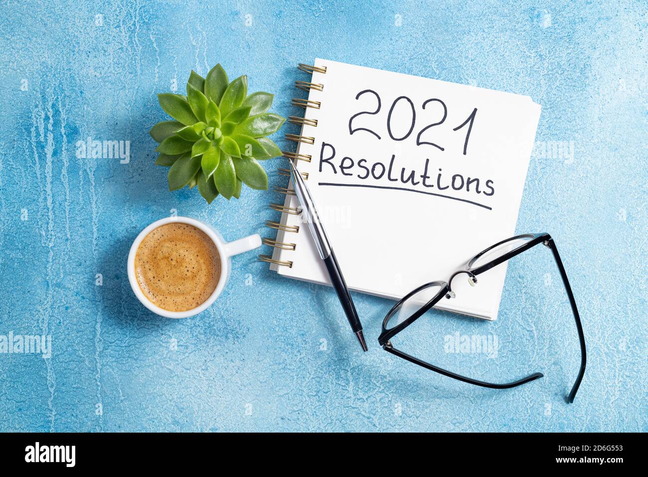 New year resolutions 2021 on desk. 2021 goals with notebook, coffee cup and eyeglasses on blue background. Goal, plan, strategy, action, idea concept. Stock Photo