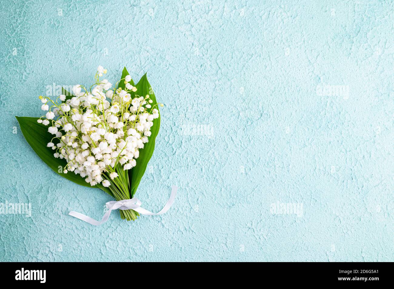 Bouquet of flowers lily of the valley on turquoise background flat lay, beautiful vintage card, top view. Spring, holidays, wedding concept. Copy spac Stock Photo
