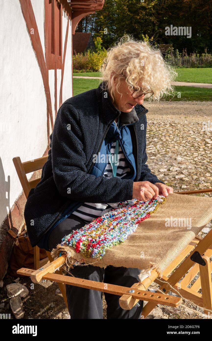 Woman rag rugging, craftwork involving weaving old scraps of cloth through hessian backing to produce a rug Stock Photo