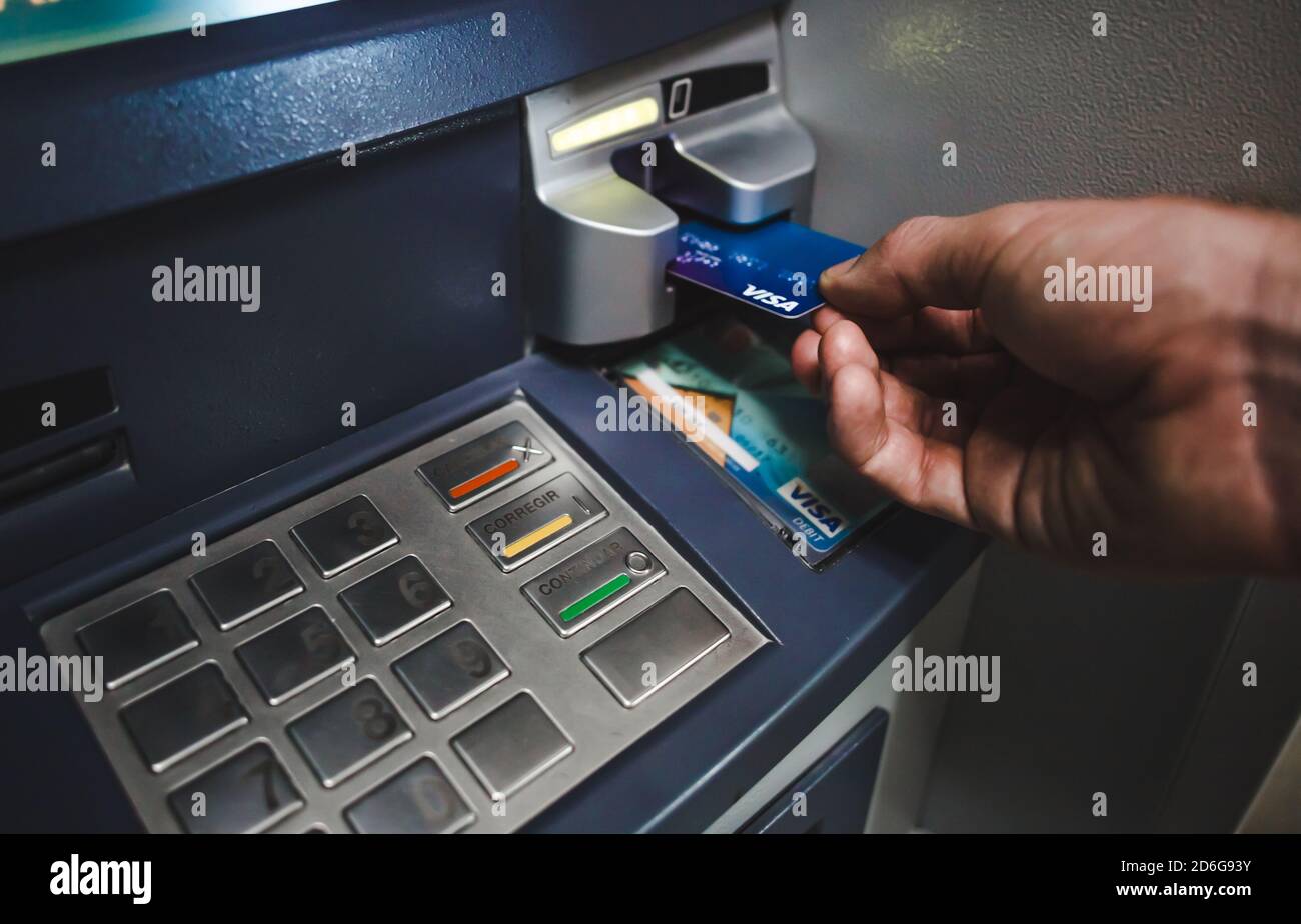 Man puts Visa Revolut debit card into ATM cash machine to withdraw money Stock Photo