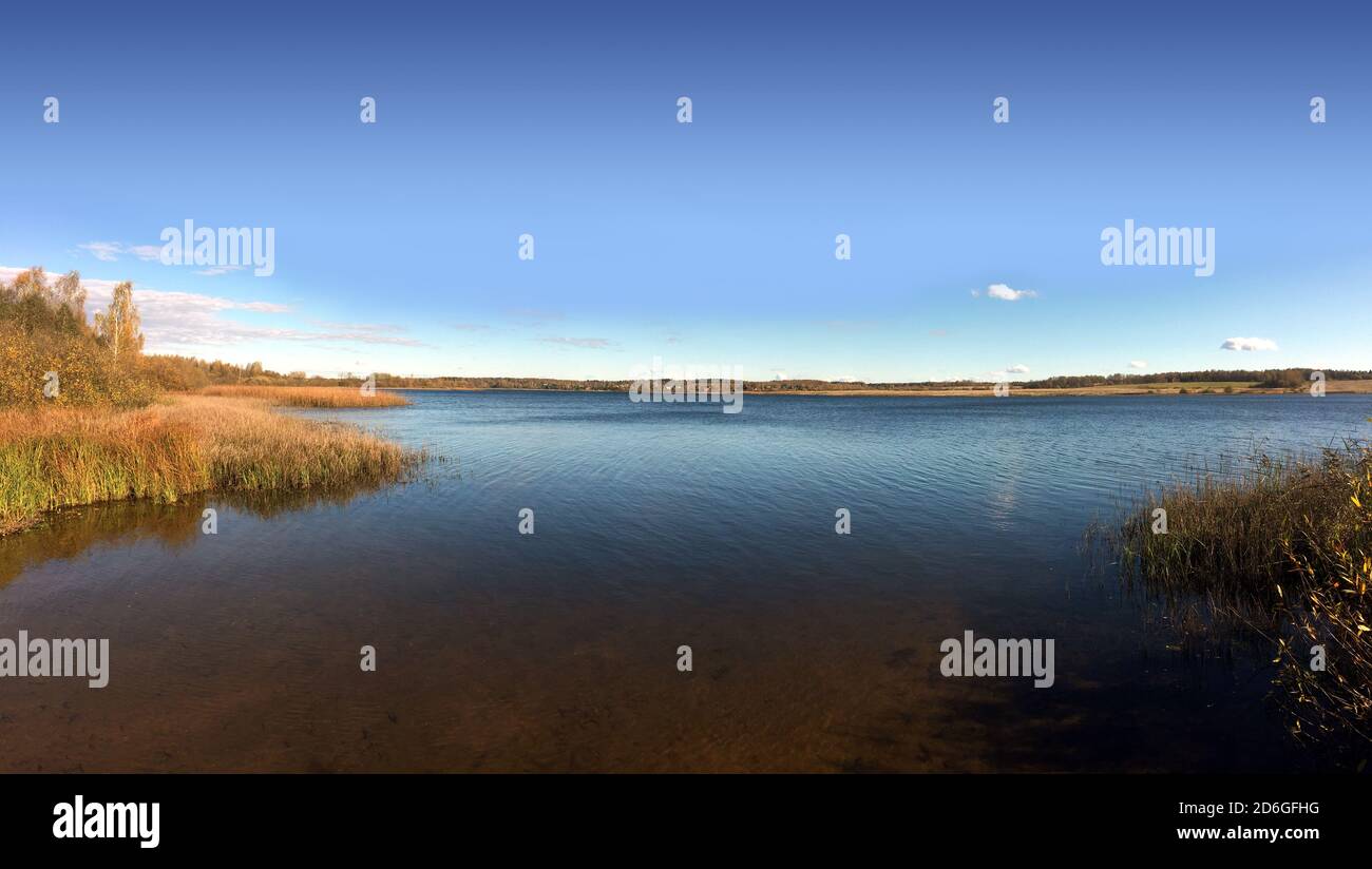 Quiet backwater on a rural lake with panoramic view of the village and forest far away on the horizon Stock Photo