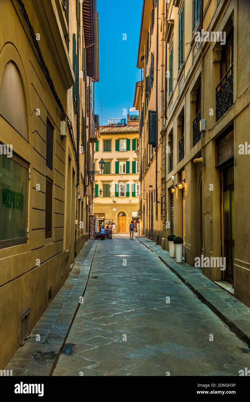 Nice portrait shot of the empty narrow alley Via dei Biffi in the old city centre of Florence, Tuscany, Italy on a sunny day with a blue sky. Stock Photo