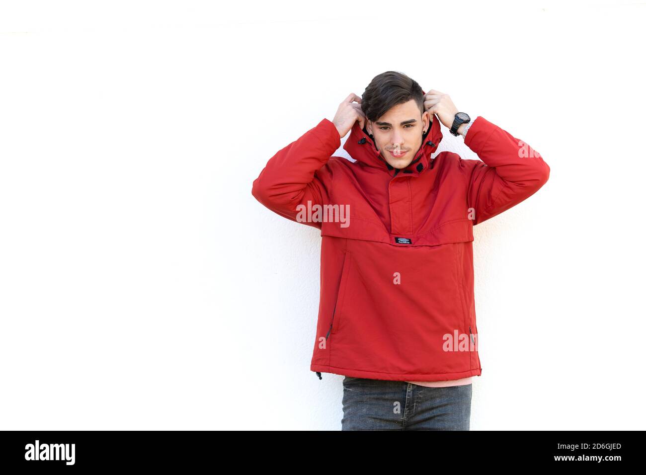 young man in red coat over white wall Stock Photo