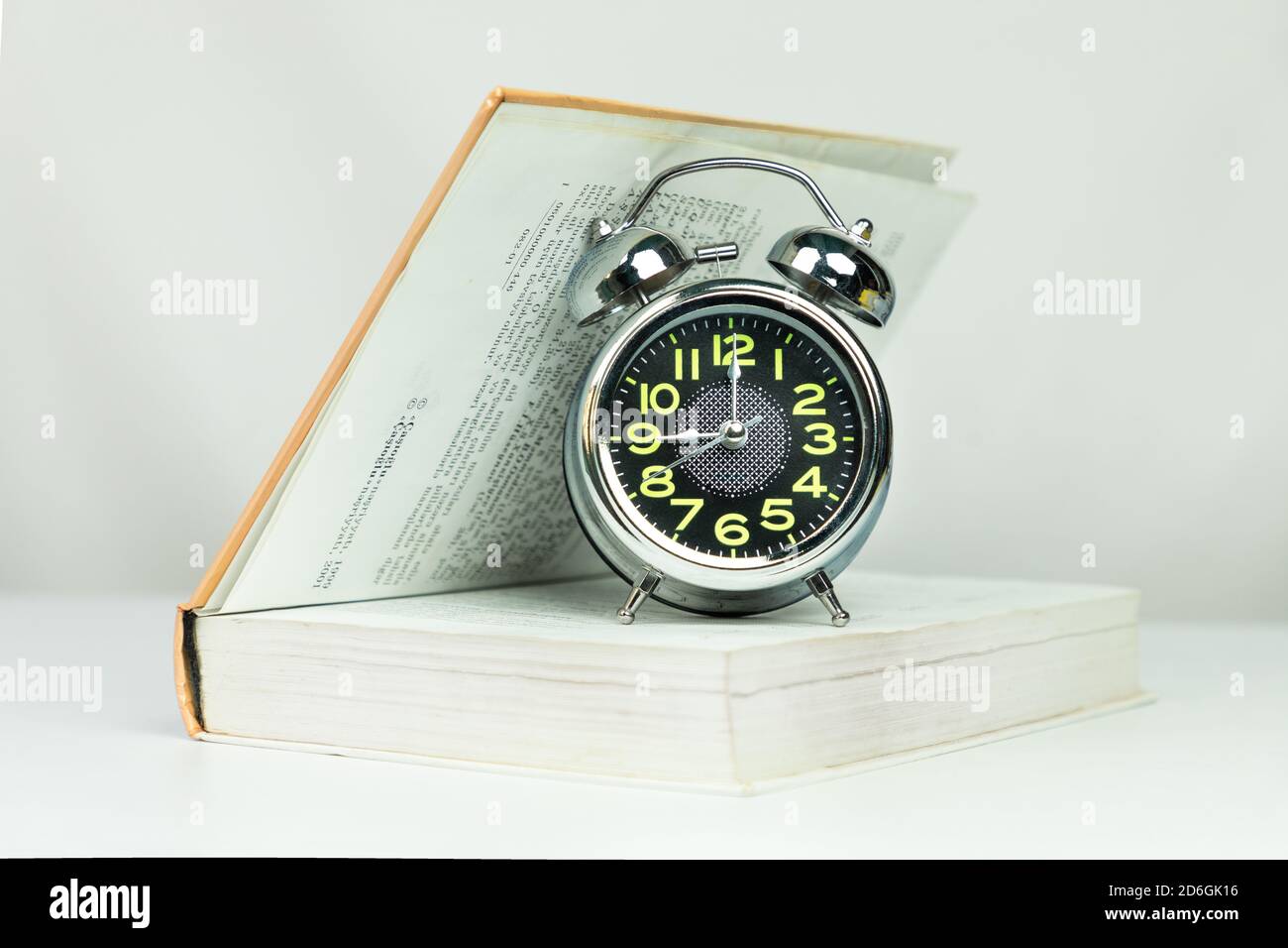 Alarm clock on half open book isolated Stock Photo Alamy