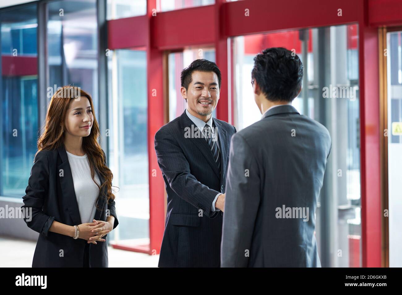 asian corporate executives shaking hands with visiting client in elevator hall of modern office building Stock Photo