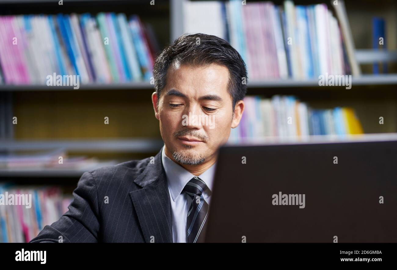 mature asian business man working in office using laptop computer Stock Photo