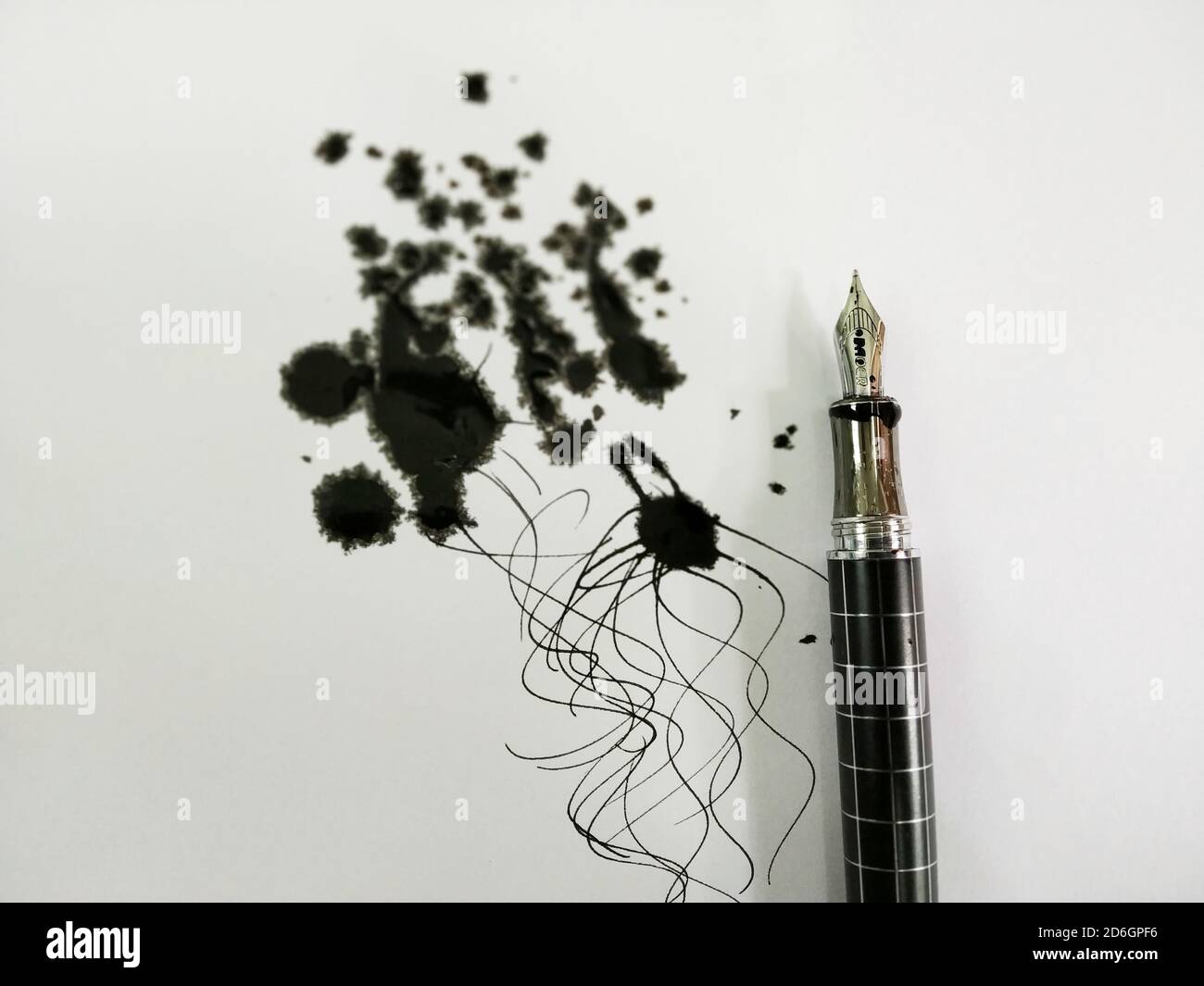 A Ink pen with black ink spread on paper Stock Photo