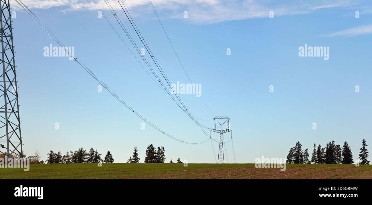 Tall steel power cable pylons supporting electricity cables over flat