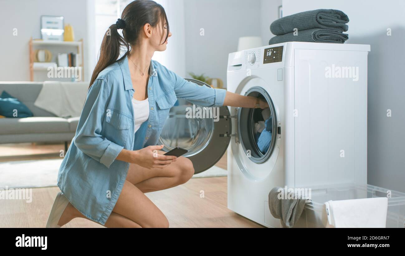 Beautiful Young Woman Sits on Her Knees Next to the Washing Machine. She  Loaded the Washer with Dirty Laundry and Configured the Wash With Her Stock  Photo - Alamy