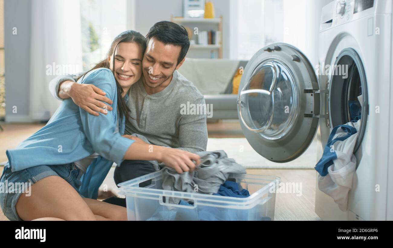 Beautiful Young Couple Sit Next to a Washing Machine at Home. They