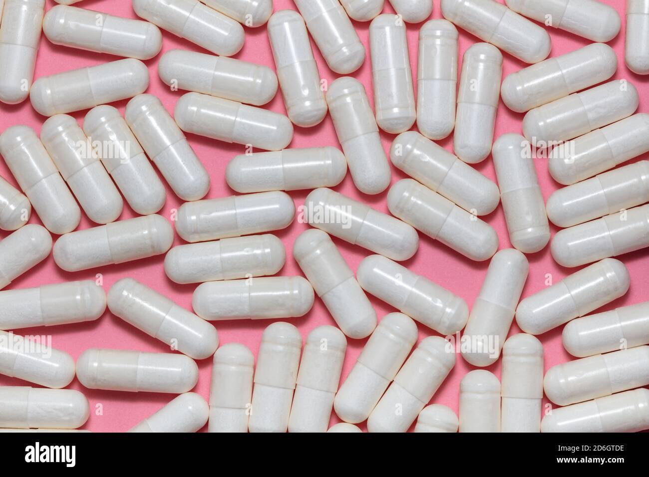 Top close up shot of white pills on pink background. Healthcare, medical and pharmaceutical concept. Stock Photo
