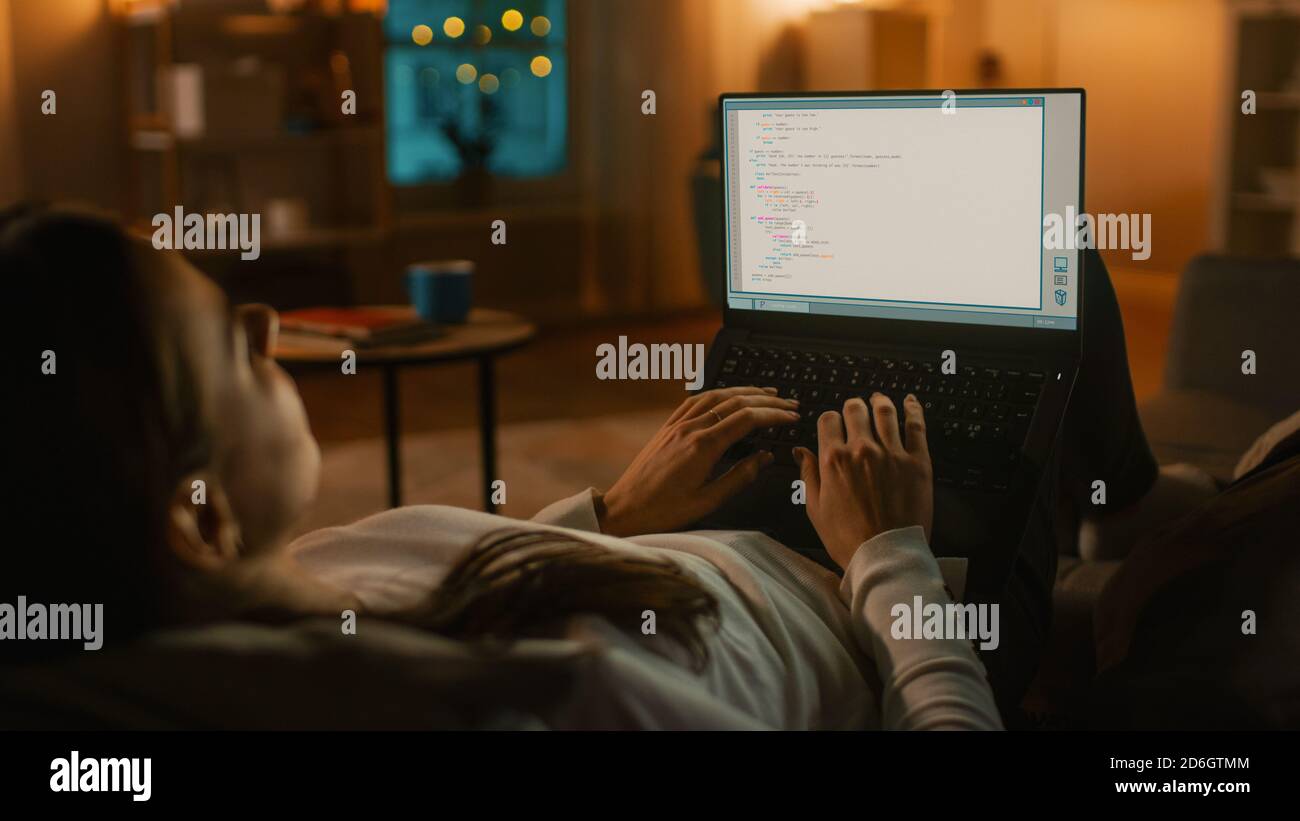 Evening at Home: Young Programmer Woman Lying on a Couch using Laptop ...