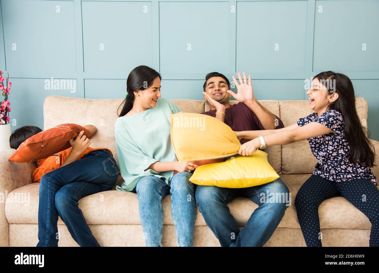 Indian Family having funny pillow fight on sofa or couch. Parents spending  free time with their small kids Stock Photo - Alamy