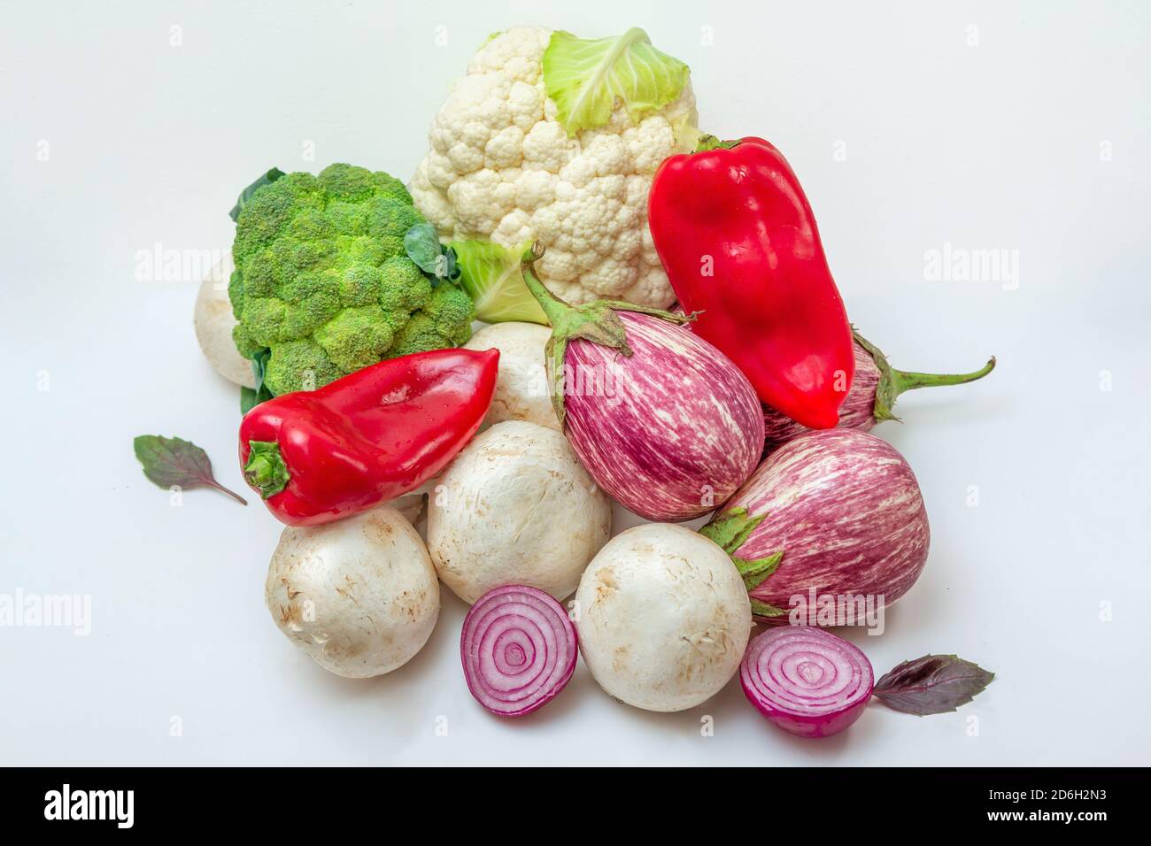 Vegetables and mushrooms on white background. Vegetarian dish ingredients - eggplants, champignons, paprika, onion, cauliflower and broccoli. Healthy Stock Photo