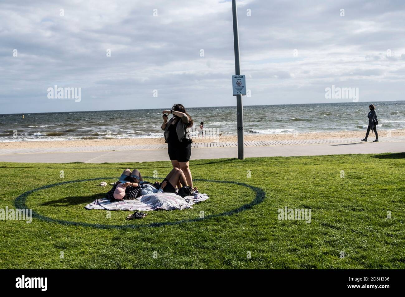 Women take pictures on the beach shore of St. Kilda, observing the social distance rule by staying inside the circle that is specially drawn.Premier of Victoria Daniel Andrews makes the official announcement of the revised roadmap that will slowly lead Victoria out of the lockdown. Stock Photo