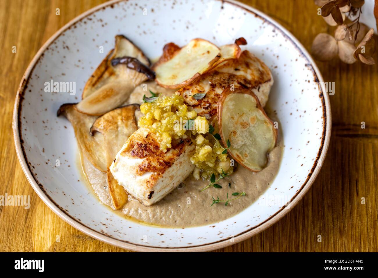 Pan fried halibut with mushroom velute, hazelnut pesto and potato crisps Stock Photo