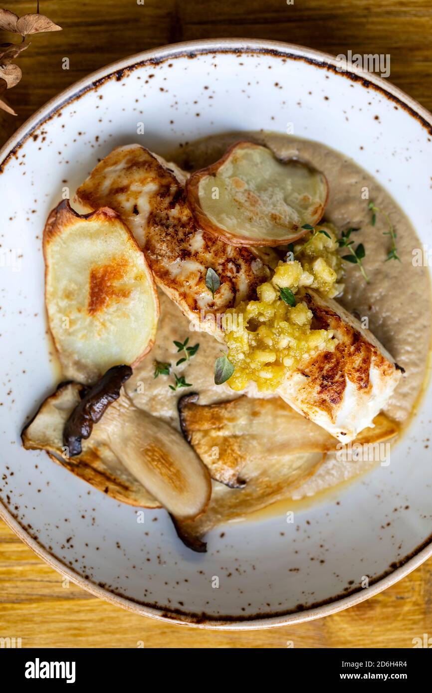 Pan fried halibut with mushroom velute, hazelnut pesto and potato crisps Stock Photo