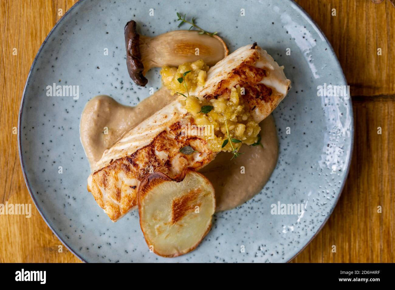 Pan fried halibut with mushroom velute, hazelnut pesto and potato crisps Stock Photo