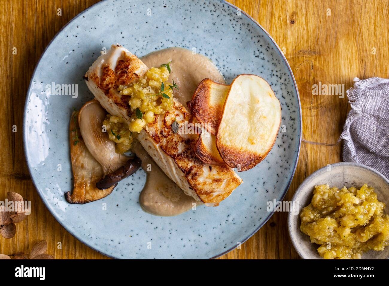 Pan fried halibut with mushroom velute, hazelnut pesto and potato crisps Stock Photo